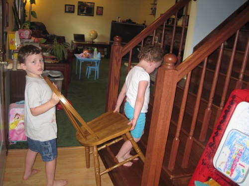 kids carrying a chair up the stairs